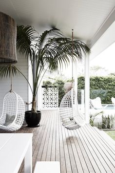 a porch with white wicker furniture and palm trees on the deck area, next to a swimming pool