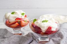 two dessert dishes with strawberries, whipped cream and mint garnish in them