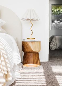 a bedroom with a bed, nightstand and lamp on the floor in front of it