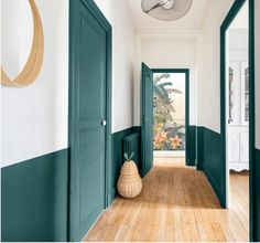 an empty hallway with green doors and wooden floors is pictured in this image from the inside