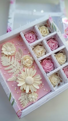 an open box filled with pink and white cupcakes on top of a table