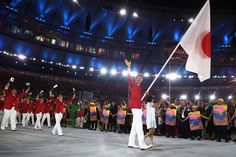 a woman holding a japanese flag in front of a group of people at a stadium