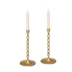 pair of brass candlesticks with chains on the ends, one candle is white and the other is gold