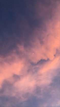 an airplane is flying in the sky at sunset or dawn with pink clouds behind it