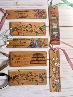 four wooden bookmarks with flowers and birds on them, one has a ribbon around it