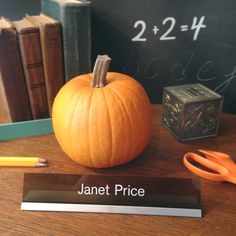 an orange pumpkin sitting on top of a desk next to a pencil and eraser