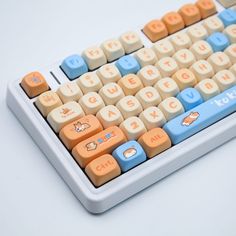 an orange and blue keyboard sitting on top of a white table next to a computer mouse