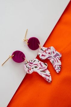 two pairs of earrings on an orange and white background