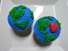 two cupcakes with green and blue frosting on a white plate, one has a red heart