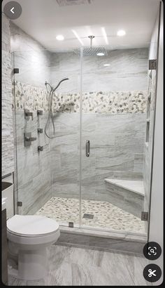 a walk in shower sitting next to a white toilet and counter top with a glass door