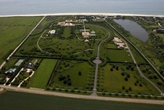 an aerial view of a large green field next to the ocean