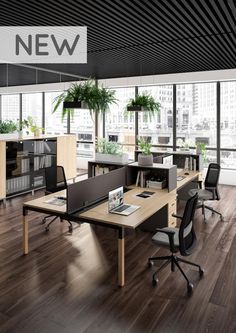 an office with wooden floors and desks in the middle, along with large windows