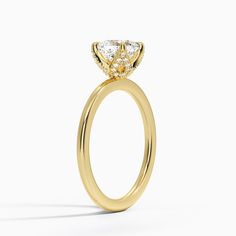 a yellow gold engagement ring with a single diamond in the center, on a white background