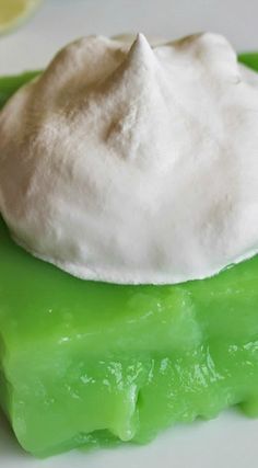 a piece of green jello with whipped cream on top