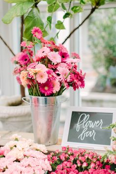 pink and white flowers are on display in a metal bucket next to a sign that says flower year