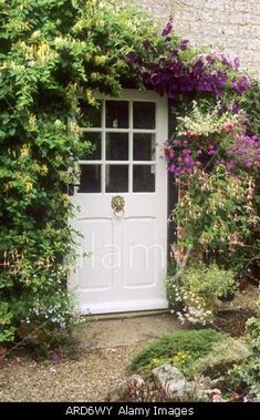 a white door surrounded by flowers and greenery