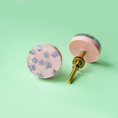 two pink knobs with blue flowers on them sitting next to each other against a green background