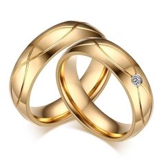 two gold wedding rings with a diamond on the top and one in the middle, sitting next to each other