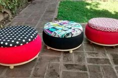 three brightly colored stools sitting on top of a brick floor next to a tree