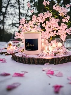 a candle and some pink flowers on a table with candles in the middle, surrounded by petals