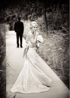 a black and white photo of a woman in a wedding dress walking down a path