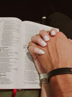 two hands holding each other over an open book