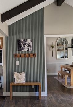 a wooden bench sitting in the middle of a living room next to a wall with pictures on it