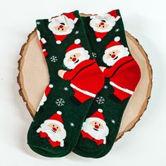 Green ankle socks with a santa claus and snowflake design. These socks are pictured on a piece of wood on a white background. Novelty Socks For Winter Gift, Novelty Winter Socks For Gifts, Novelty Winter Socks As Gift, Novelty Winter Socks For Gift, Cute Green Socks For Stocking Stuffers, Playful Christmas Socks For Stocking Stuffers, Fun Christmas Gift Socks, Playful Winter Socks For Gift, Cute Christmas Gift Socks