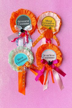 three ribbons with badges attached to them sitting on a pink surface, one for best customer and the other for best customer