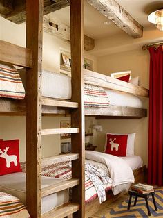 bunk beds in a room with red curtains and striped rugs on the floor next to each other