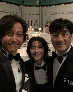 two men and a woman in tuxedos posing for a photo