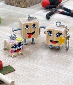 three wooden toy blocks with faces and eyes on them sitting on a table next to tools