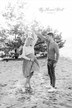 an engaged couple dancing on the beach during their engagement photo session in black and white