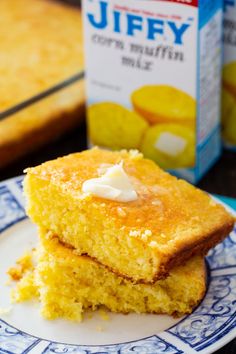 two pieces of cornbread on a blue and white plate with a carton of jelly in the background