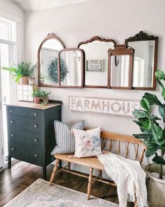 a bench with pillows and plants on it in front of three mirrors that say farmhouse