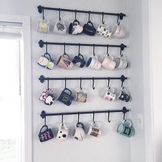 coffee mugs are lined up on the wall and hanging from metal racks with hooks