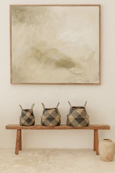 three baskets on a bench in front of a painting