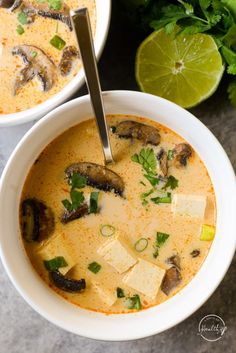 two white bowls filled with soup and topped with tofu, parsley and cilantro