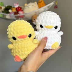 a hand holding two small crocheted stuffed animals, one yellow and the other white