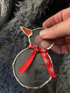 a hand holding a glass ornament with a red ribbon around it's neck