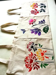 three bags with flowers painted on them sitting on a table