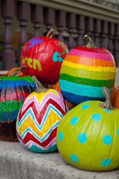 colorful painted pumpkins sitting on top of a cement slab