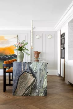 a kitchen with marble counter tops and wooden flooring in front of a painting on the wall