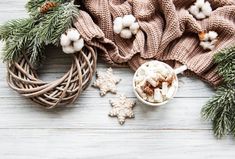 a cup of hot chocolate with marshmallows and pine cones on a wooden table