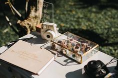 a table with a camera, notebook and other items on it next to a tree