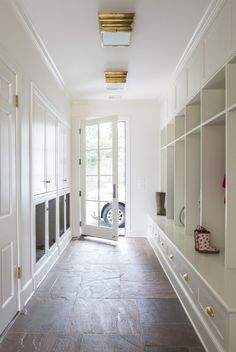 an empty room with white cabinets and large open doors that lead to the front door