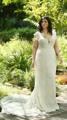 a woman in a white dress standing on a wooden walkway