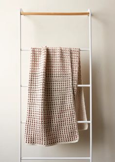 a towel rack with two towels hanging from it's sides and a white wall in the background