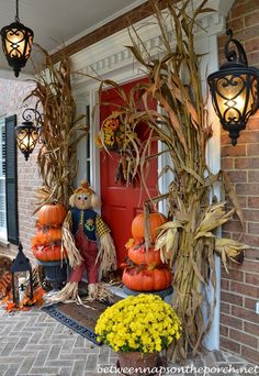 a front porch decorated for halloween with pumpkins and corn stalks