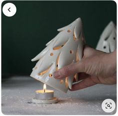 a person lighting a candle in front of a christmas tree ornament